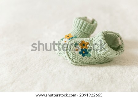 Beautiful knitted baby socks with embroidery, handmade knitted booties on a white background with copy space. Pregnancy and motherhood concept, first birthday, handmade socks, baby warm clothes Royalty-Free Stock Photo #2391922665