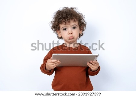 Beautiful two year old toddler with curly hair wearing casual clothes over white studio background feeling sad. 