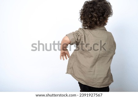 Beautiful two year old toddler with curly hair wearing casual clothes over white studio background back view, dancing baby boy. 