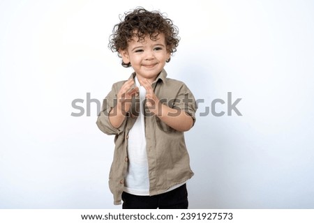 Beautiful two year old toddler with curly hair wearing casual clothes over white studio background clapping.  Royalty-Free Stock Photo #2391927573