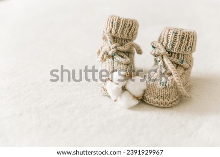 Knitted baby socks, booties on a white background with copy space. Pregnancy and motherhood concept, first birthday banner, handmade socks, baby warm clothes, handmade knitted socks, hobby. Royalty-Free Stock Photo #2391929967