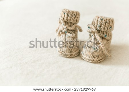 Knitted baby socks, booties on a white background with copy space. Pregnancy and motherhood concept, first birthday banner, handmade socks, baby warm clothes, handmade knitted socks, hobby. Royalty-Free Stock Photo #2391929969