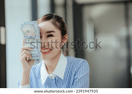 Happy beautiful Asian businesswoman holding money in hand Smartphone and laptop on table in office investment ideas success in business