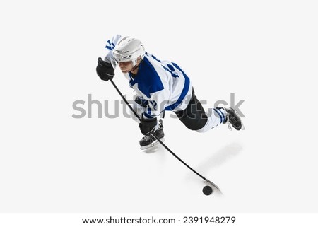 Top view. Competitive young man, hockey player in motion, playing, training on rink against white studio background. Concept of professional sport, competition, game, tournament, game, action