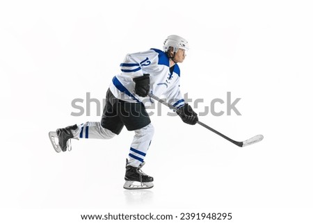 Young man, motivated athlete, hockey player in motion with stick on rink, training against white studio background. Concept of professional sport, competition, game, tournament, game, action