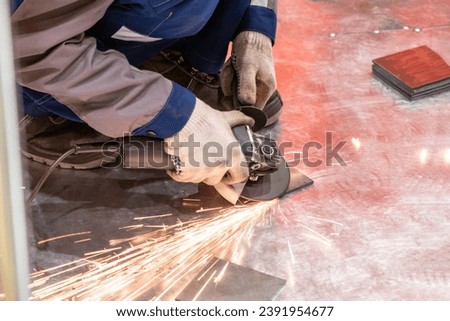 Grinding metal plates. Master hands with grinding machine. Worker aligns edges of metal sheet. Metalworking during construction. Worker with grinding machine. Metalworking process.