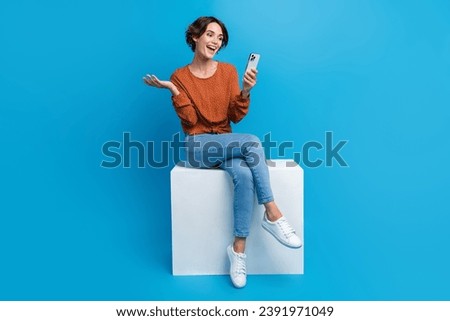 Full size photo of attractive young woman sit cube video call friend wear trendy brown clothes isolated on blue color background