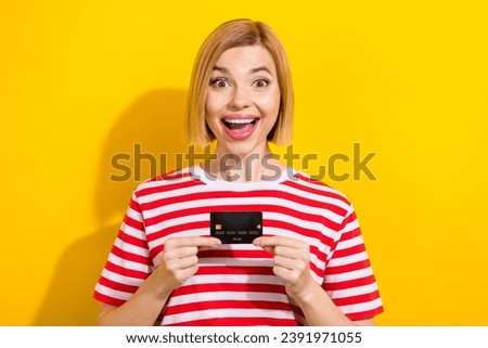 Photo of astonished cheerful successful girl wear stylish summer clothes hand hold bank card isolated on yellow color background