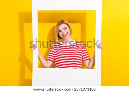 Portrait of gorgeous pretty girl with short hairdo wear stylish t-shirt hands hold photo frame isolated on bright yellow background