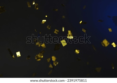 Shiny golden confetti falling down on dark blue background