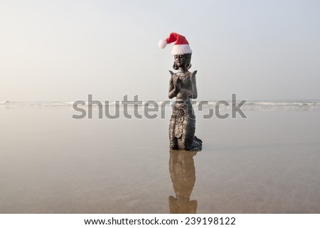Santa Budda statuette in the christmas bonnet on the beach