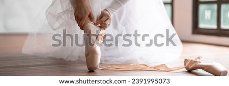 Ballerina in ballet shoes. Asian girl tying ribbons of toe shoes. ballet dancer preparing and wearing ballet shoes in dance studio prepares for a rehearsal Royalty-Free Stock Photo #2391995073