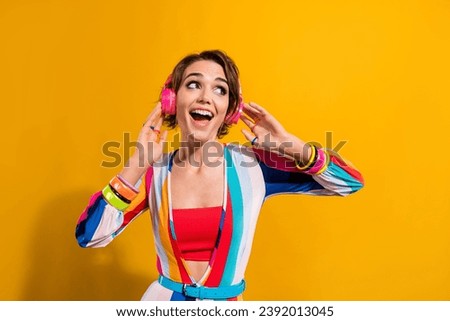Photo of excited funky lady wear striped costume enjoying music headphones looking empty space isolated yellow color background