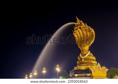 The Naga Monument (Buddhist sculpture) at night with illuminated and spray water along Mekong river, Riverside attraction in the city of Nakhon Phanom province, Northeastern Thailand also called Isan. Royalty-Free Stock Photo #2392018563