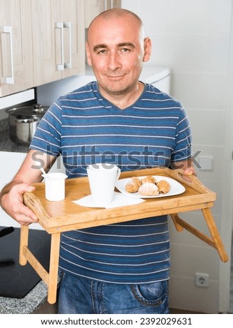Man holding wood salver of breakfast in Royalty-Free Stock Photo #2392029631