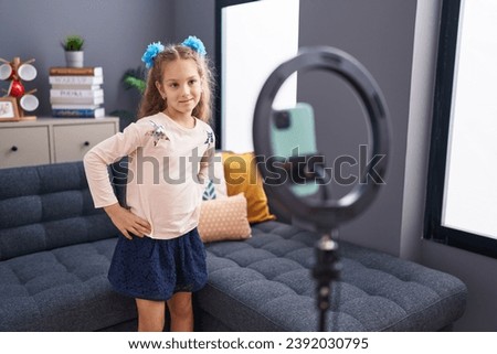 Adorable caucasian girl recording video dancing at home