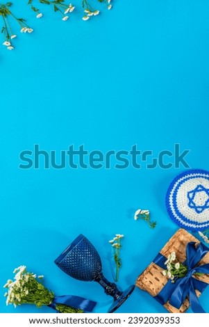 Pesah jewish Passover holiday celebration concept. Jewish kippah with a Star of David, matzah, wineglass. Blue background with empty copy space. Royalty-Free Stock Photo #2392039353