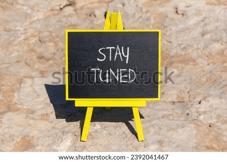 Stay tuned symbol. Concept words Stay tuned on beautiful black chalk blackboard on a beautiful beach stone background. Business, support, motivation, psychological and stay tuned concept. Copy space.