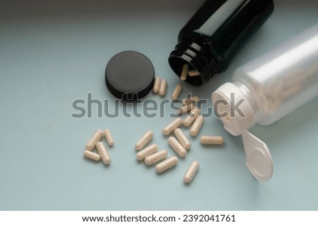 Pharmaceutical medicine pills and capsules spilling out of pill bottle.
