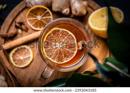 Craft mulled wine in a transparent glass on a black background, decorated with dried oranges, cinnamon and ginger