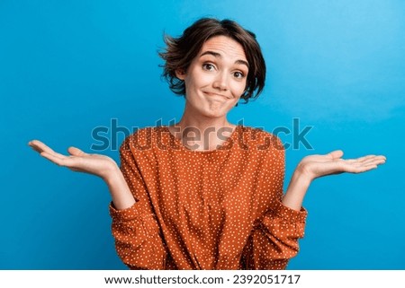 Photo portrait of lovely young lady hands shrug shoulders indifferent dressed stylish brown garment isolated on blue color background Royalty-Free Stock Photo #2392051717