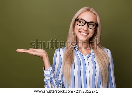 Photo portrait of blonde lovely young lady palm hold look empty space wear trendy striped garment isolated on khaki color background