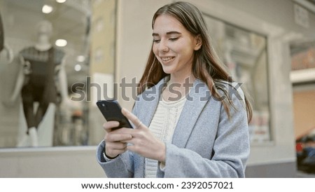 Young hispanic woman using smartphone smiling at street