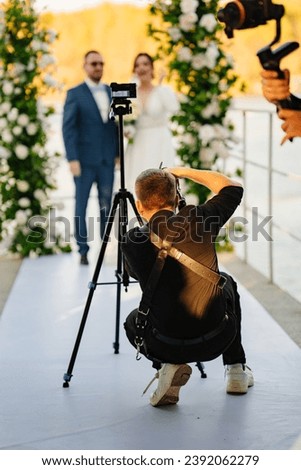 Photographer taking pictures of the bride and groom at the off-site ceremony. Selective focus. Professional videographer and wedding photographer.