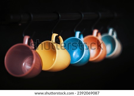 Colorful empty ceramic cups hanging on wall.
