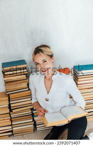woman and many stacks of educational books to read in the library