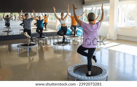 Fitness enthusiasts participating in a trampoline workout class in a sunny gym Royalty-Free Stock Photo #2392073281