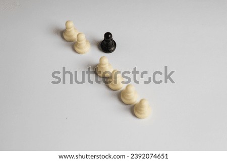Line of white pawn pieces and black piece is out of the line, on white background, racism concept