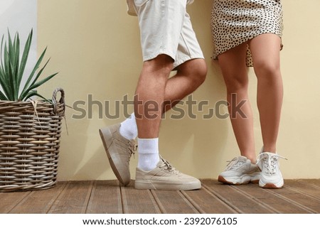 Woman and man wearing stylish sneakers near beige wall, closeup Royalty-Free Stock Photo #2392076105