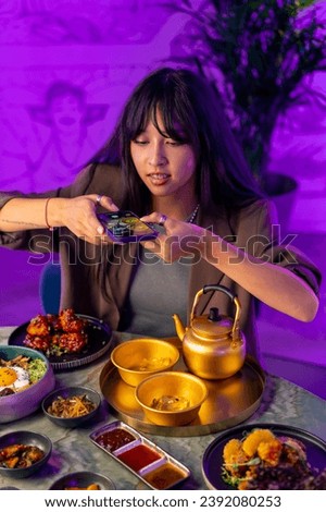 a young girl takes a picture on a smartphone of serving a drink in a teapot in Korean restaurant