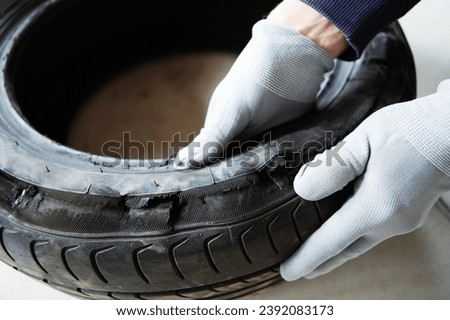 A low-quality car tire that has not passed the crash test. Examination of automotive rubber and a test for wear resistance in a specialized service. Close-up. selective focus Royalty-Free Stock Photo #2392083173