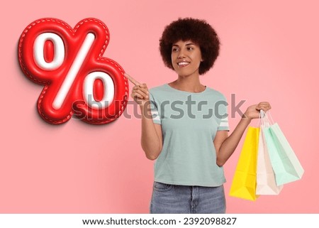 Discount offer. Happy woman with paper shopping bags pointing at illustration of percent sign on pink background