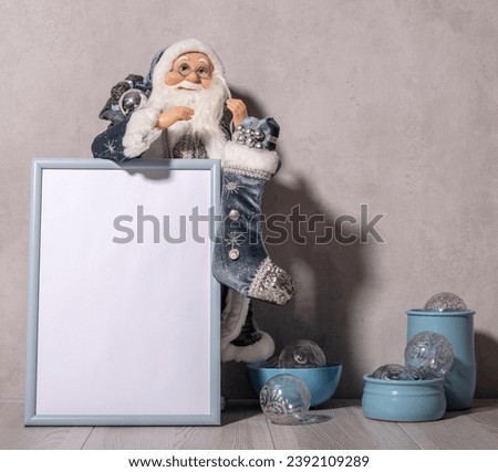Christmas template with blank photo frame, figurine of Santa Claus and new year baubles in bowls.
