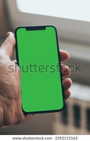 High-quality stock photo of a modern smartphone with a green screen image. editable