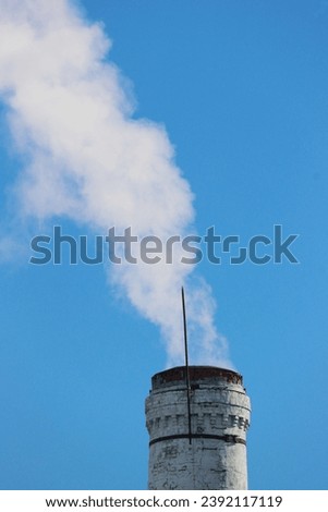 Carbon Emissions Concept. An old brick pipe from a heating station with smoke coming from it.