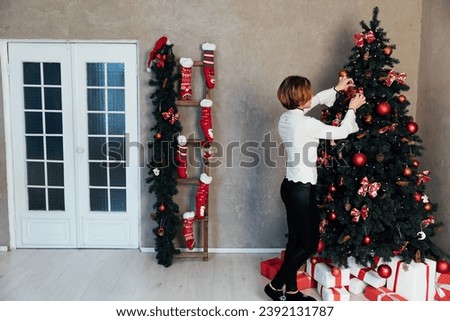 Woman decorating christmas tree with gifts for new year