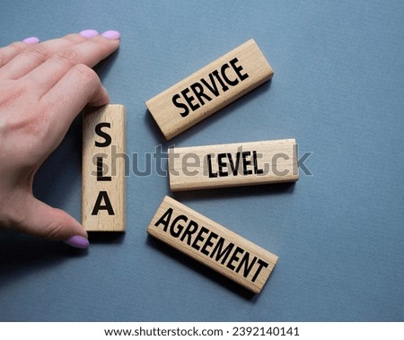 SLA - Service Level Agreement. Wooden blocks with word SLA. Businessman hand. Beautiful grey background. Business and Service Level Agreement concept. Copy space.