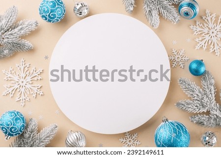 Making this Christmas atmosphere. Top view photo of holiday baubles, frost-kissed fir branches, snowflakes on beige background with blank circle for ad or text