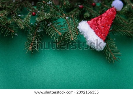 Christmas background with fir branches and Santa Claus hat on a green background