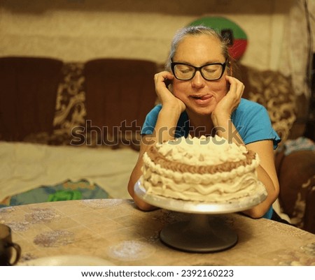 A middle-aged woman admires a birthday cake on the table