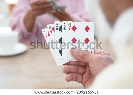 Closeup hands of asian elderly person spending free times with friends by playing cards at home after retirement happily, new edited.