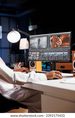 Detailed image of a creative male individual editing a movie on his desktop computer. Selective focus on the pc monitor displaying the work of a freelance videographer, filmmaker.