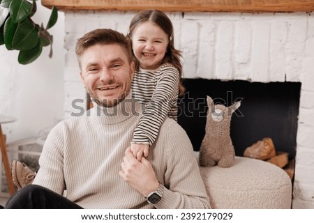 Happy father's day. Adorable child daughter and young single dad are embracing and kissing at home, feeling love and affection. Family of two is having fun and spending time together.