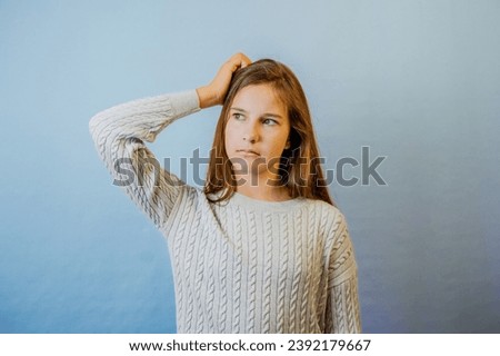 Thinking face, thoughtful emotions of teenager girl. Thoughtful teenage child girl on blue isolated background. Portrait of a kid thinking. Pensive girl