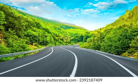 Panoramic road landscape among green mountains. View of asphalt road in beautiful nature landscape. Road view in the beautiful nature of Europe. Bavaria, Germany.