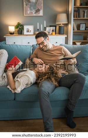 Adult couple man and woman Caucasian husband and wife in a relationship real book hold books on the sofa bed at home in the apartment reading leisure bonding family concept real people copy space Royalty-Free Stock Photo #2392195993